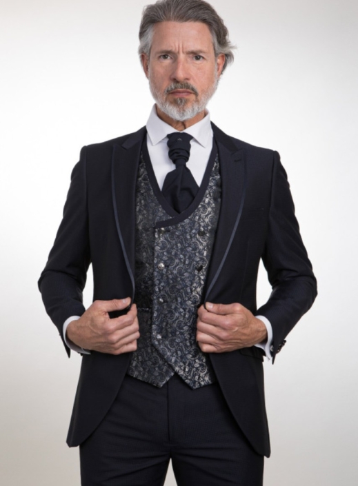 Traje marino en tejido de microdibujo y vivo en solapas, chaleco y corbatón, pantalón liso. Camisa a elegir por el cliente